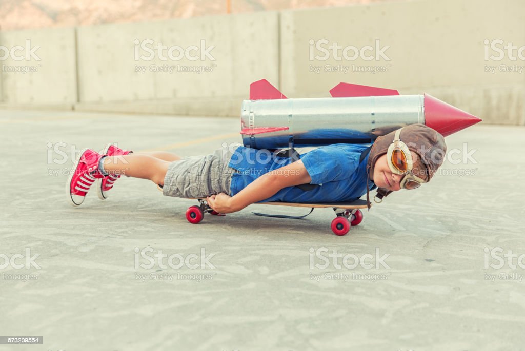 young-boy-dreams-of-flying-with-rocket-picture-id673209554